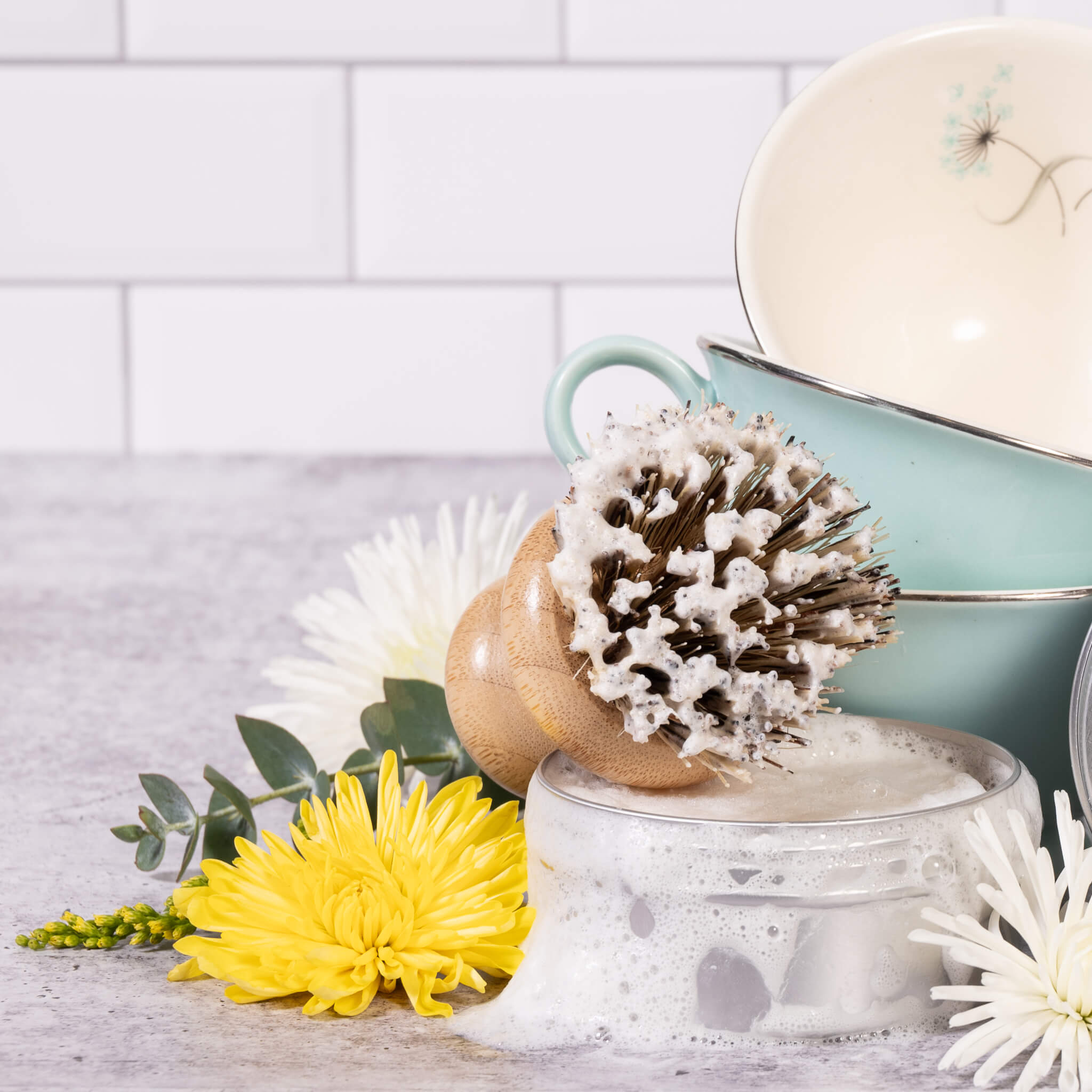 A turquoise mug and flowers on a concrete counter.