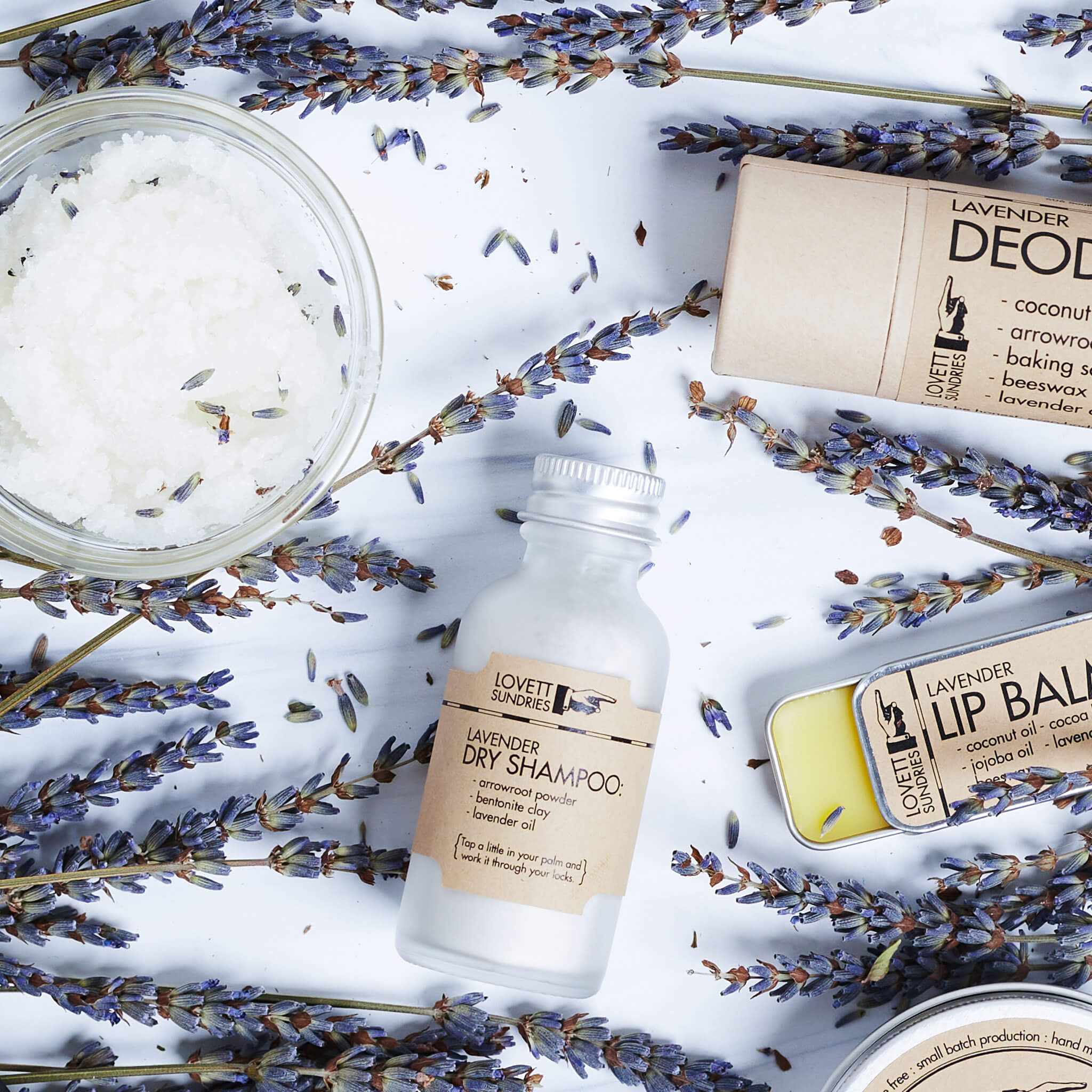 Lavender scented products laying on a bed of lavender flowers.