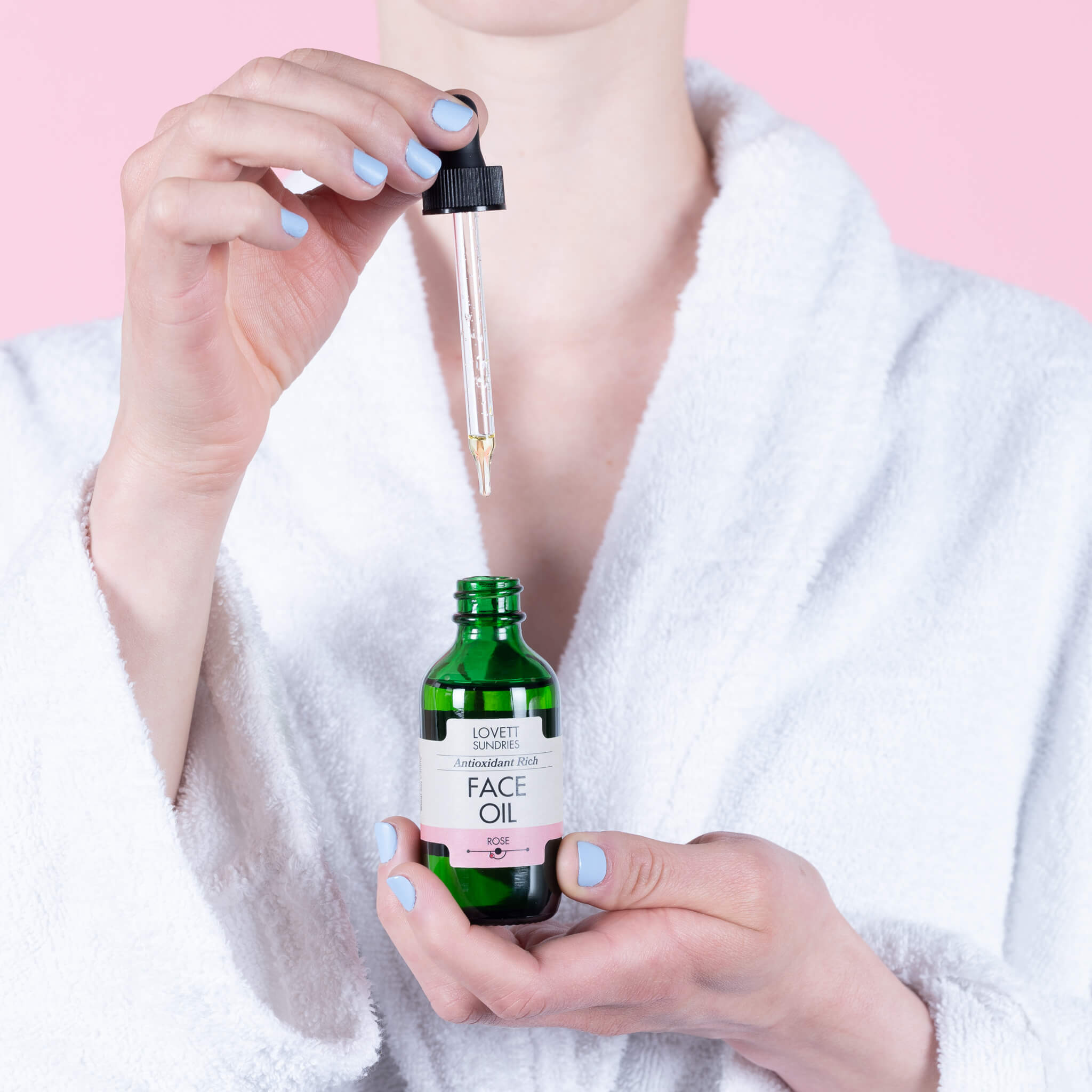 Kari pulling a dropper out of her green glass bottle of all natural organic Face Oil.