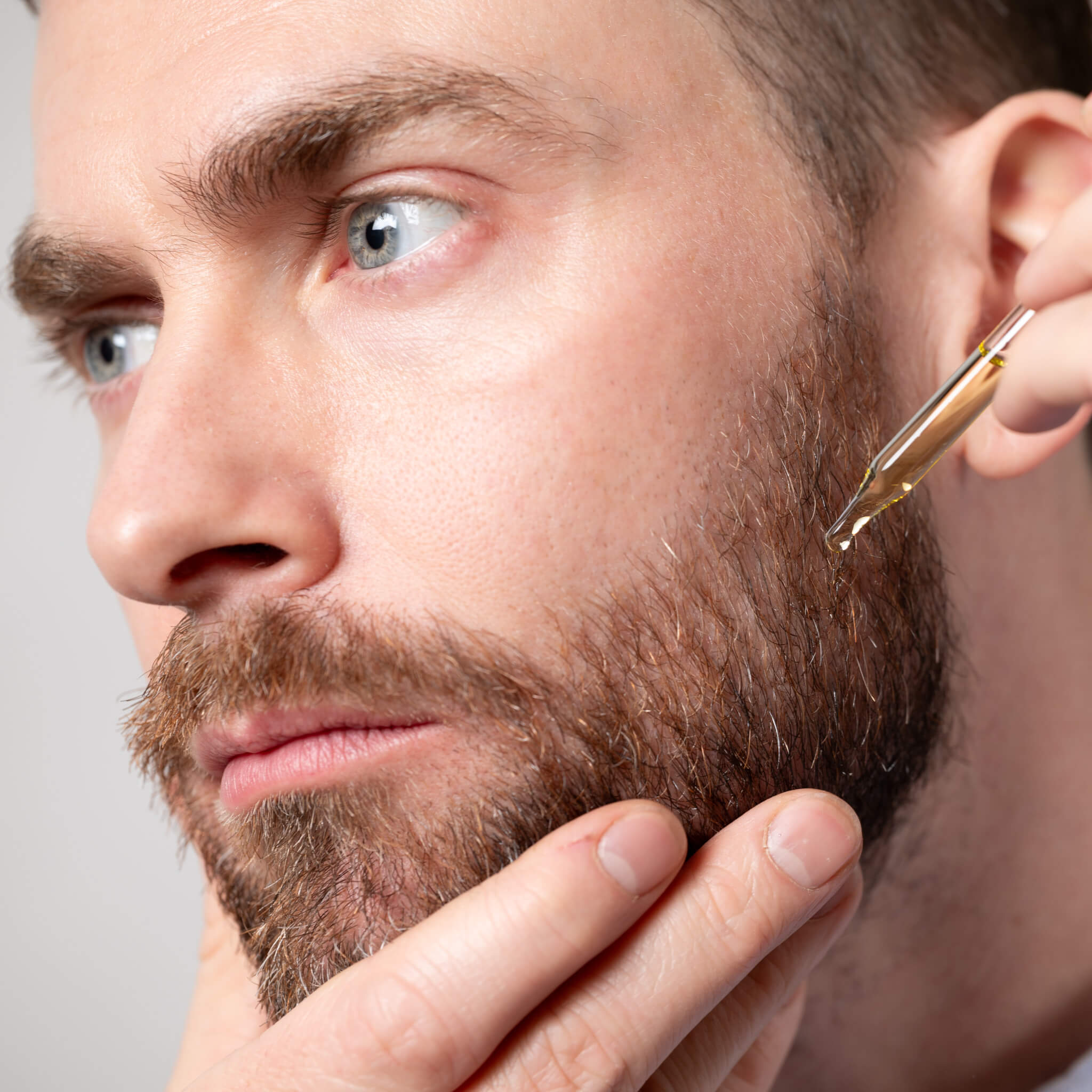John applies a vial of Beard Oil directly to the whiskers on his cheek.