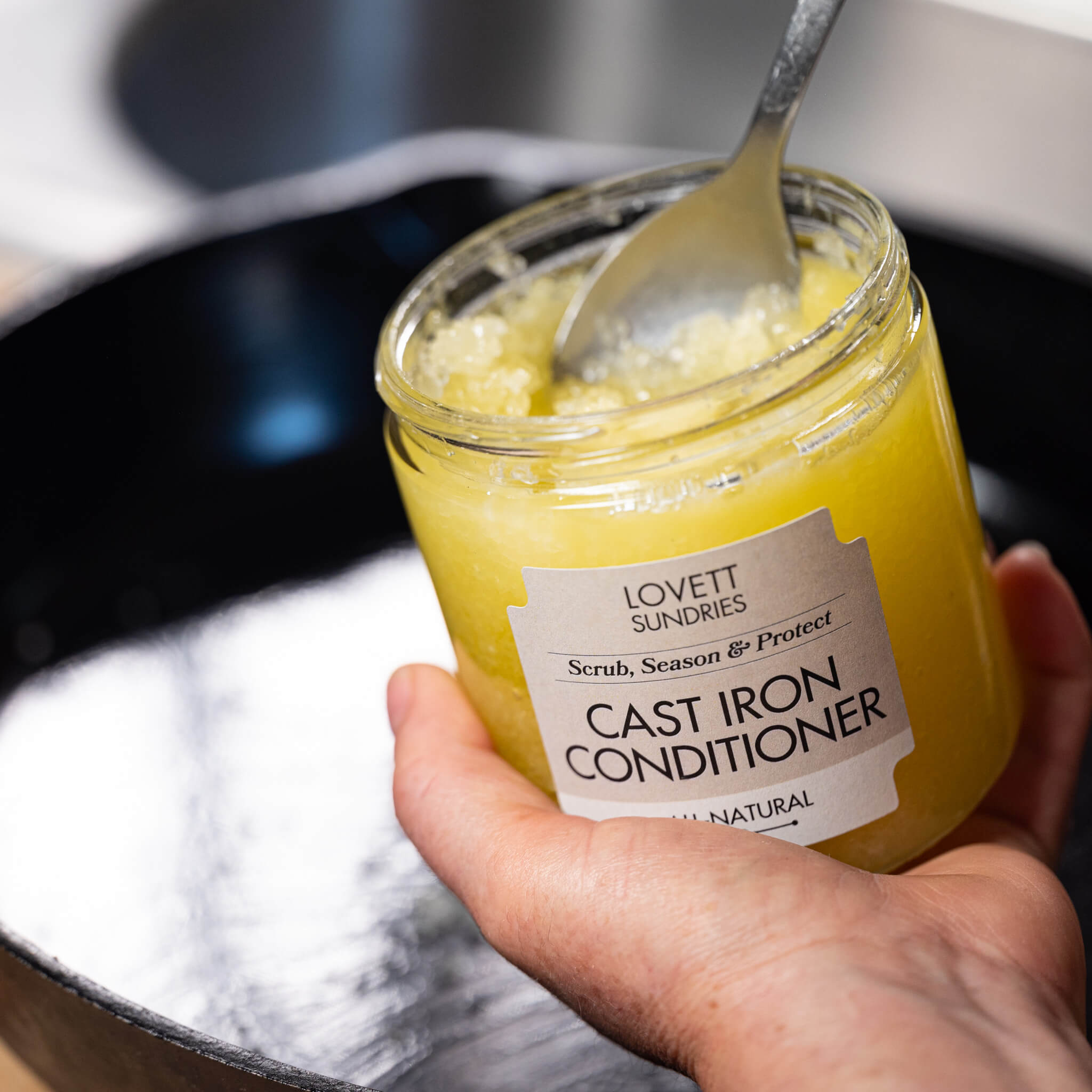 Marit spooning Cast Iron Conditioner in to her skillet to clean and season it.