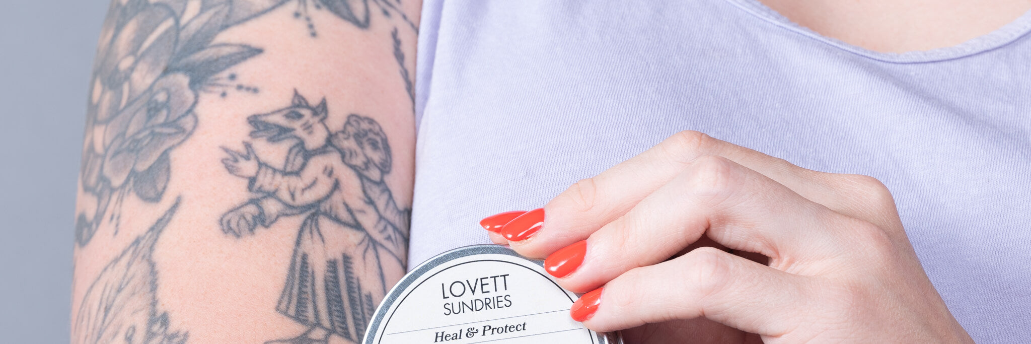 Kelly with a tin of tattoo balm on her tattooed arm.