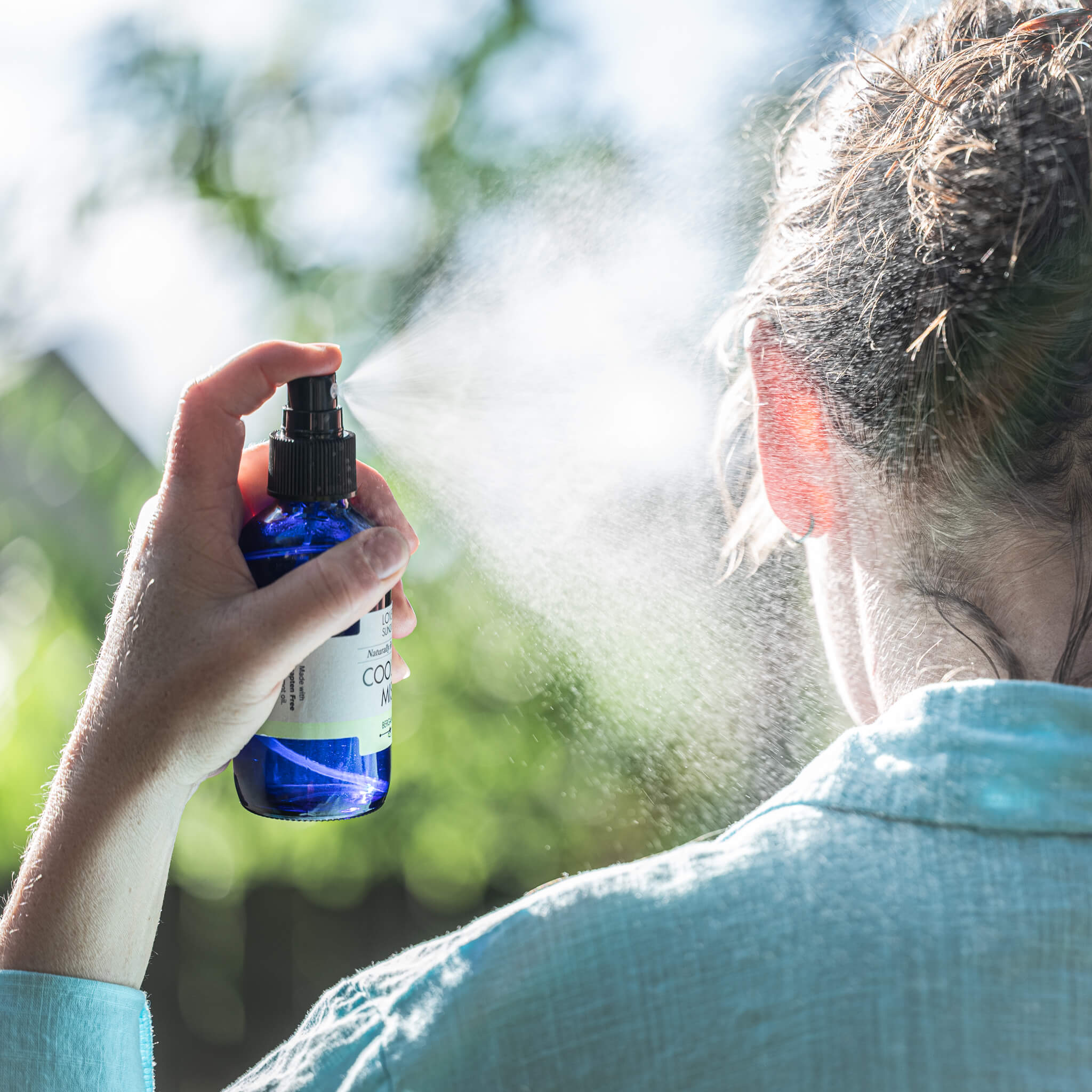 Marit spritzing all natural cooling mist on her neck on a hot day.
