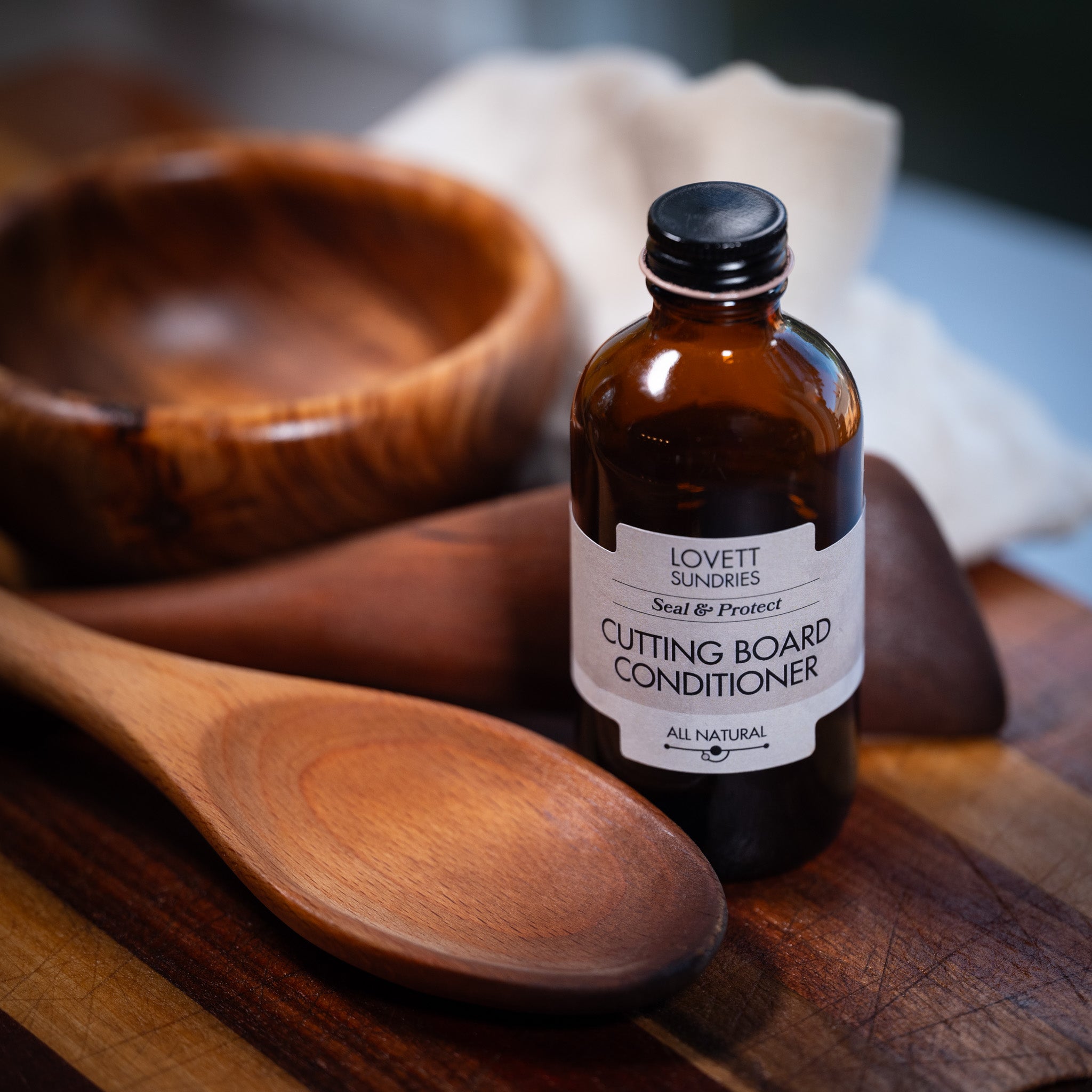 Cutting Board Conditioning Oil with freshly wooden kitchen utensils and cuttingboard.