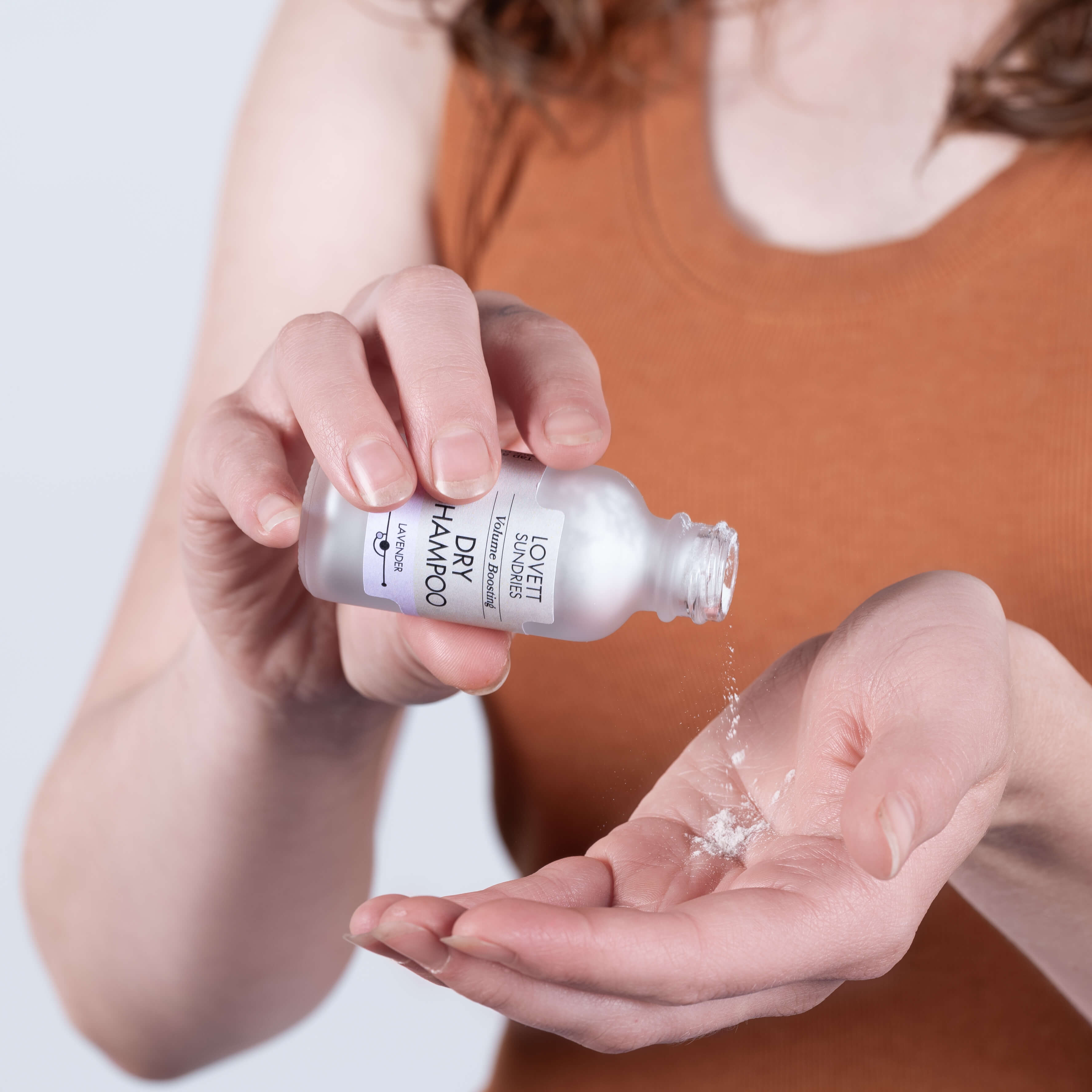Steph tapping some dry shampoo into her hand from a zero-waste glass bottle.