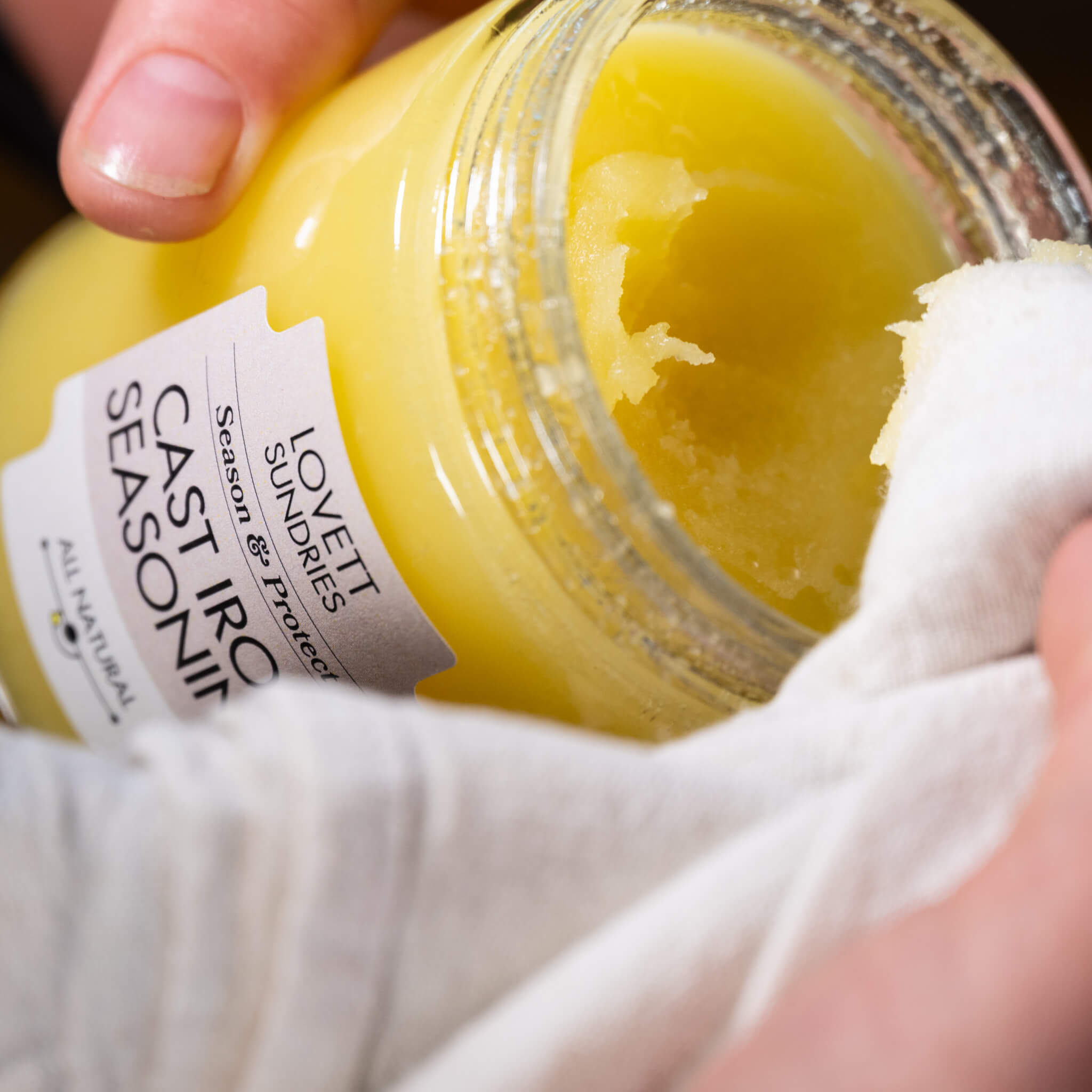 Marit scooping some Cast Iron Seasoning Oil out of the beautiful glass jar with a cloth rag.