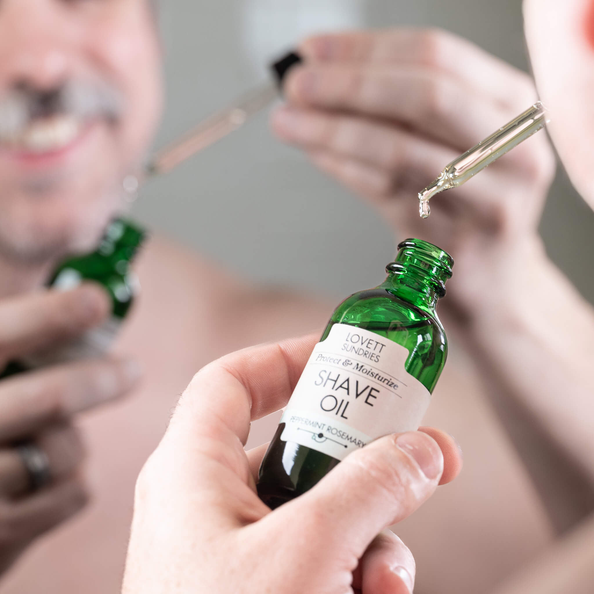 Man removing a glass dropper from a green bottle of Shaving Oil before shaving.