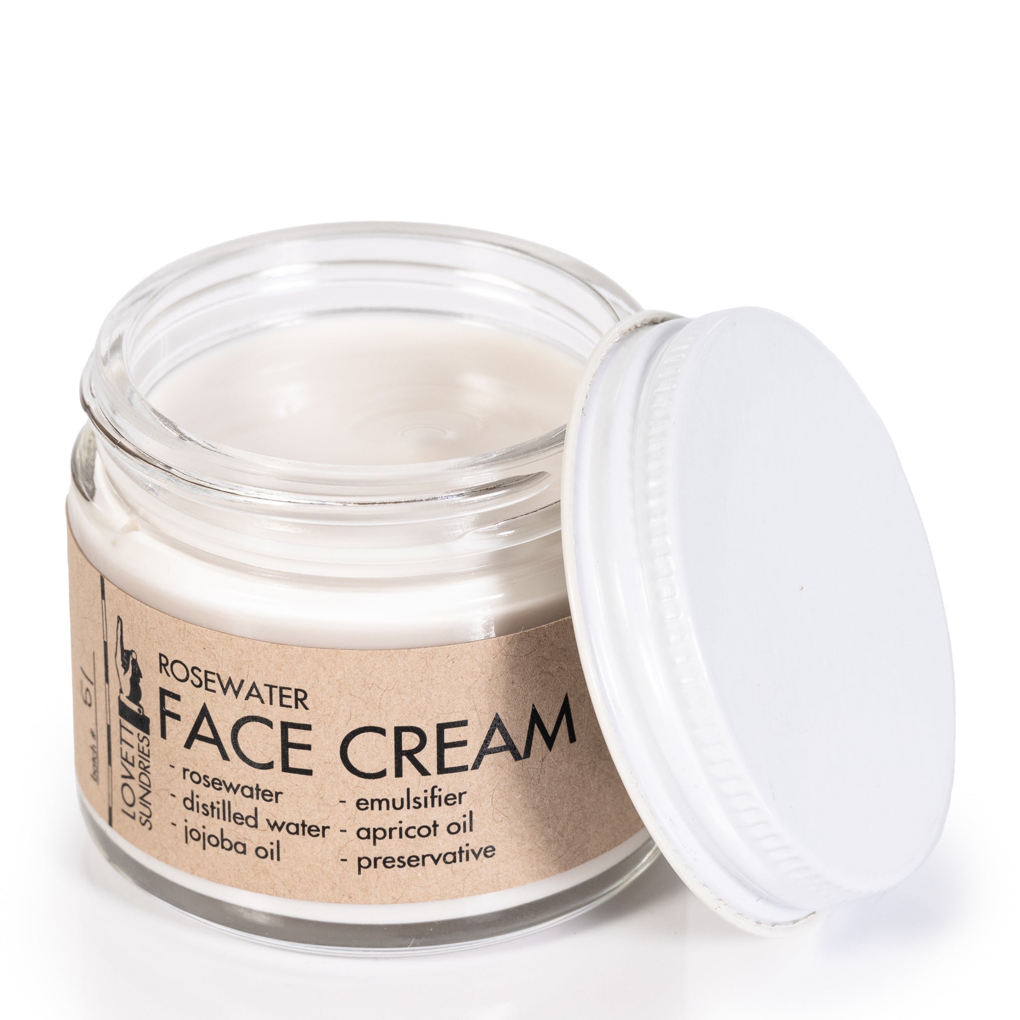 Open glass jar of moisturizing rosewater face cream wrapped in a kraft paper label with the lid on the side.