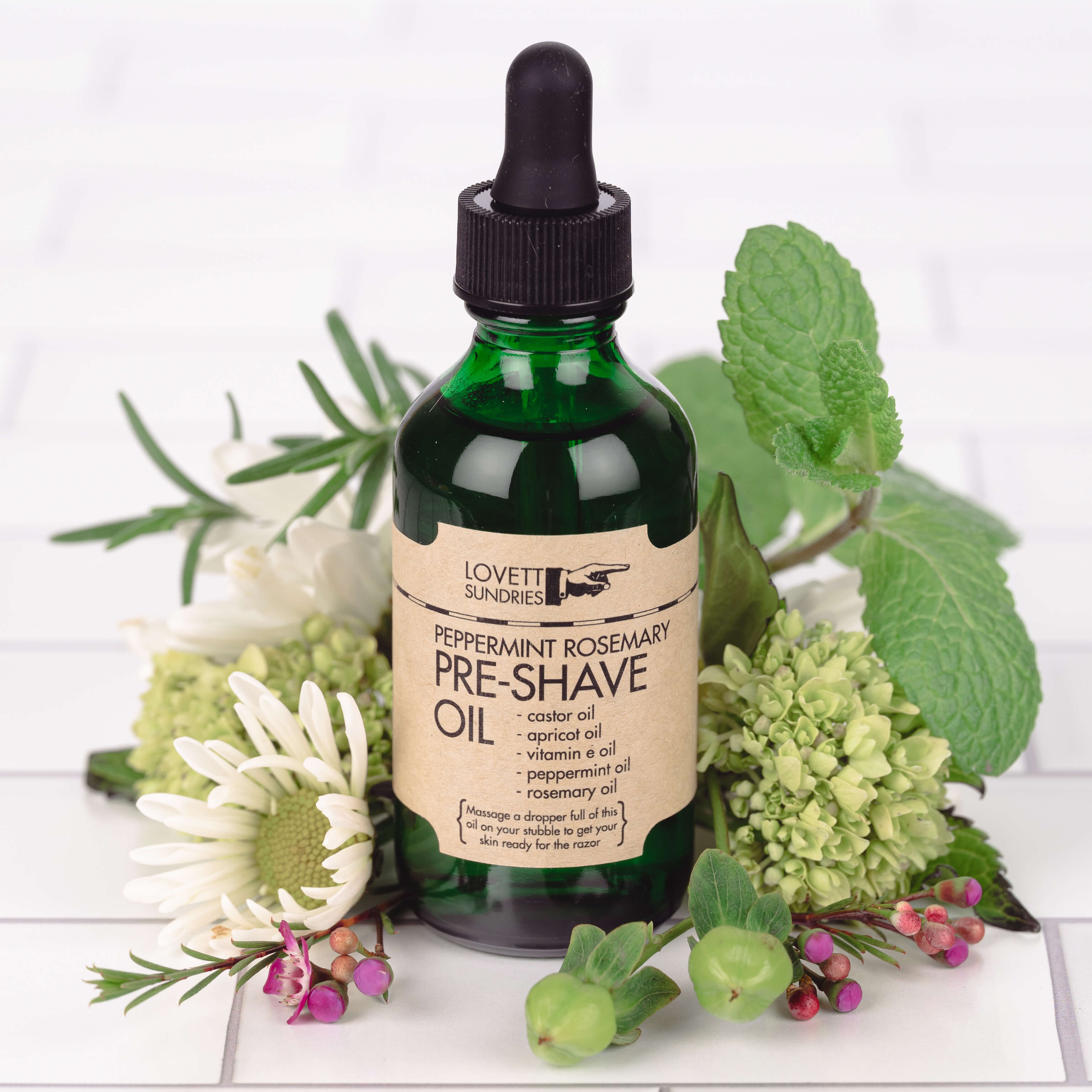 Peppermint Rosemary Shave Oil surround by flowers.