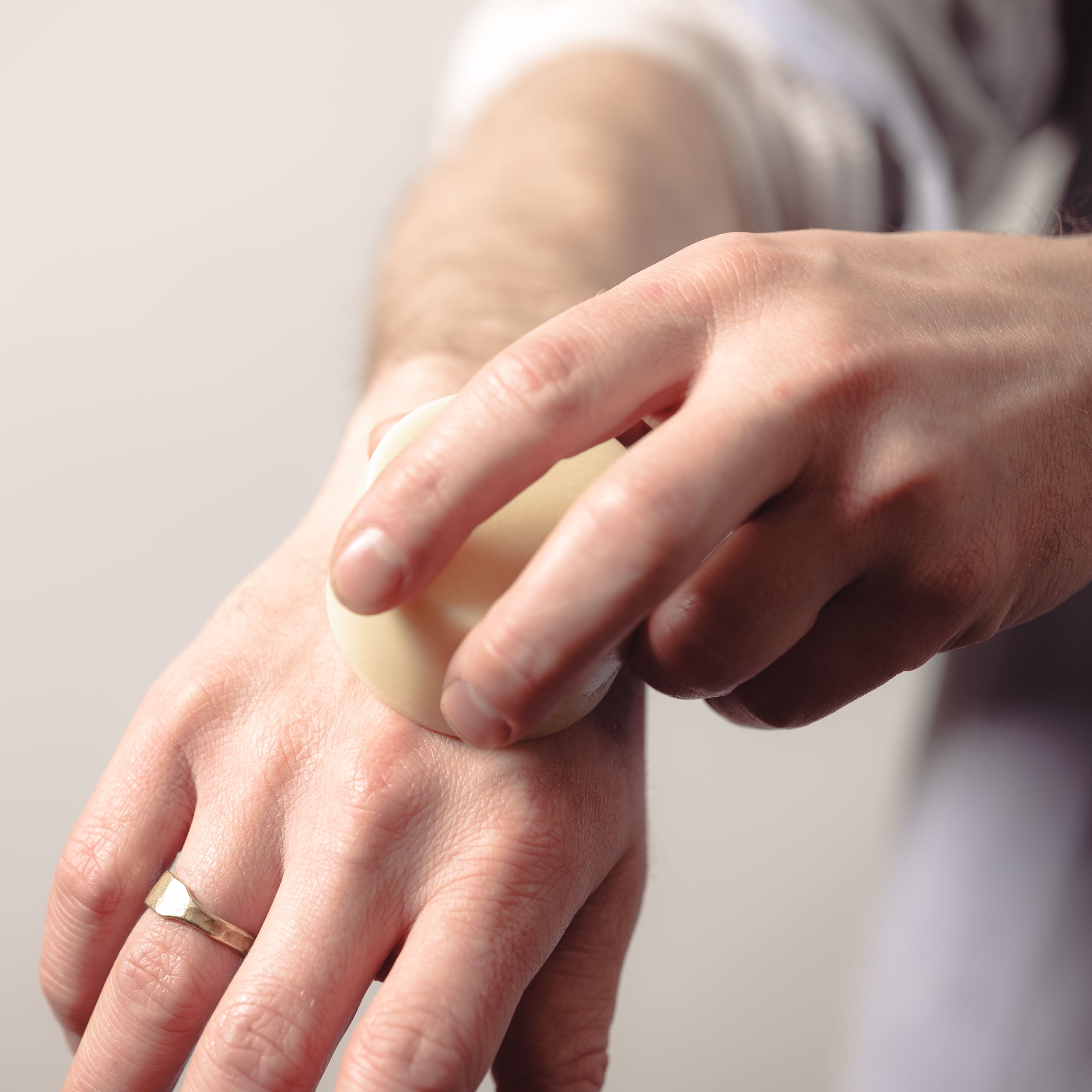 A person using a solid lotion bar on their arm.