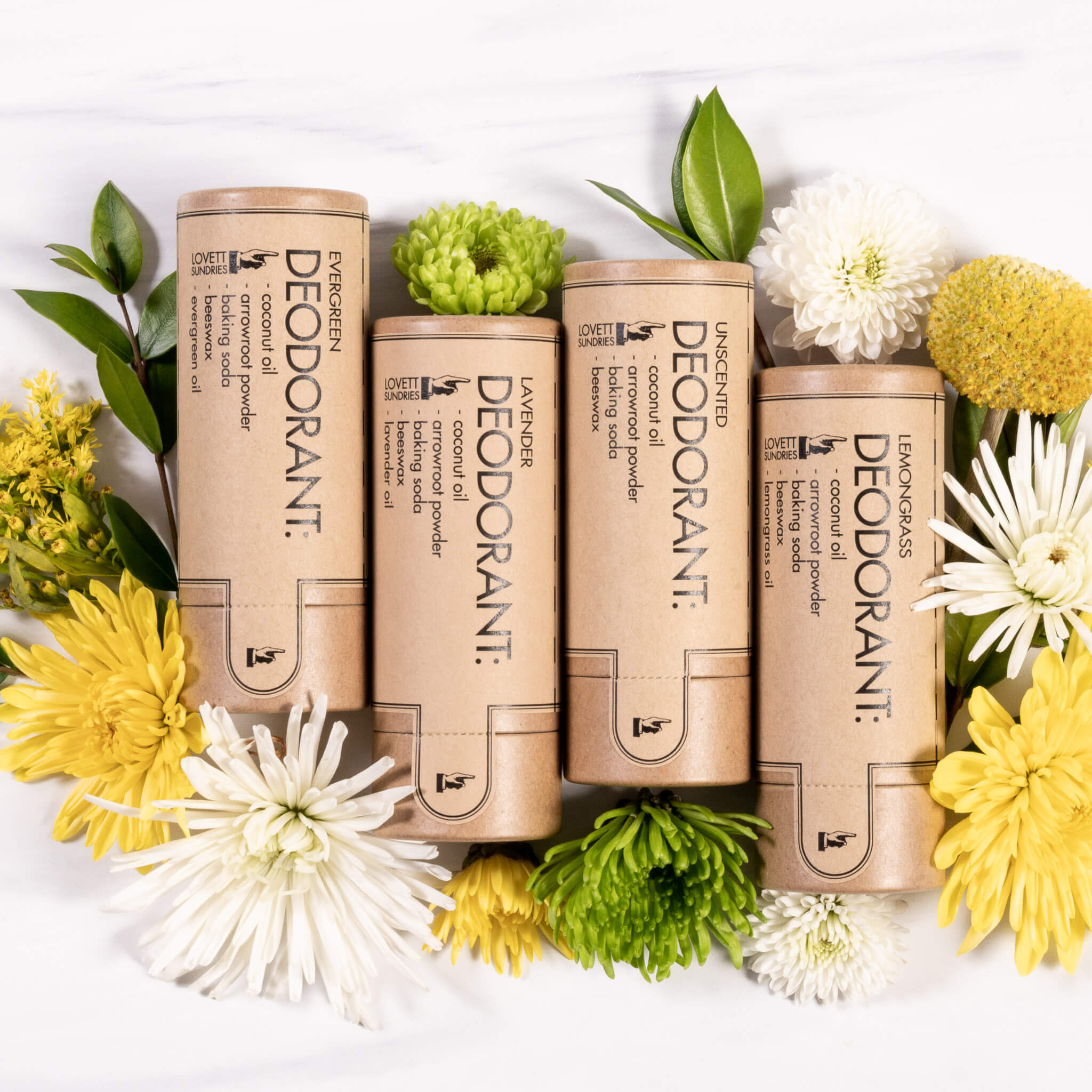 Four natural deodorant bars nestled in colorful flowers. 