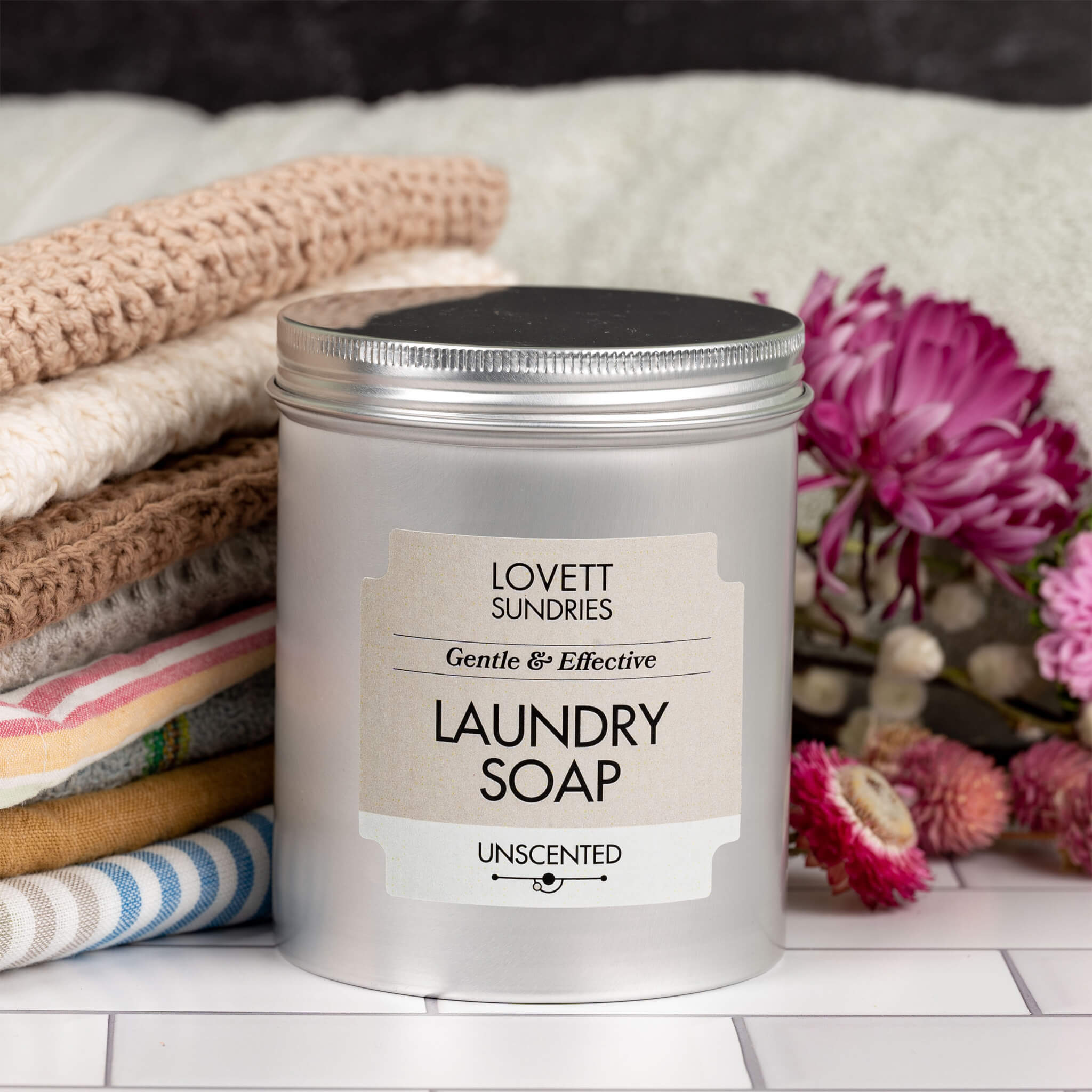 natural laundry soap in a tin with laundry and flowers in the background.