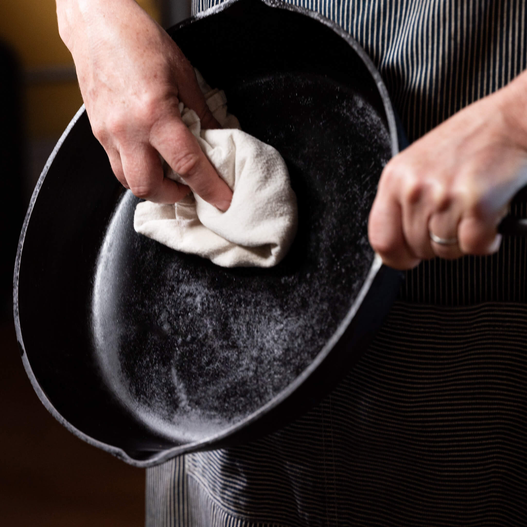 Marit wiping down a freshly scraped and oiled cast iron pan.