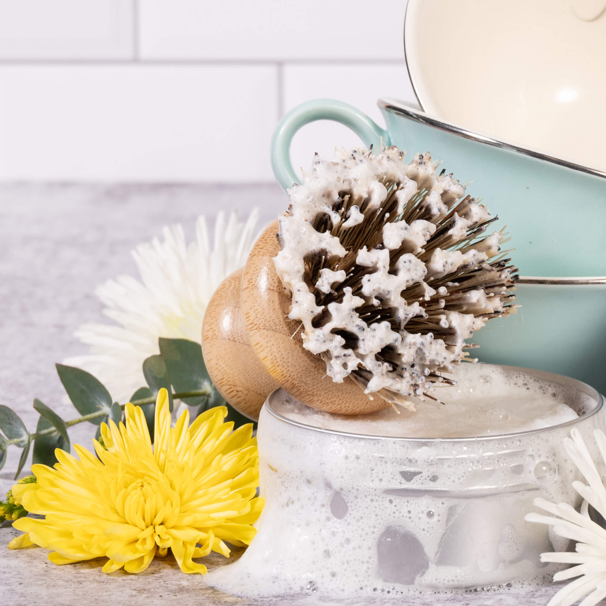 A natural bristle dish scrub brush with lather from the solid dish soap.