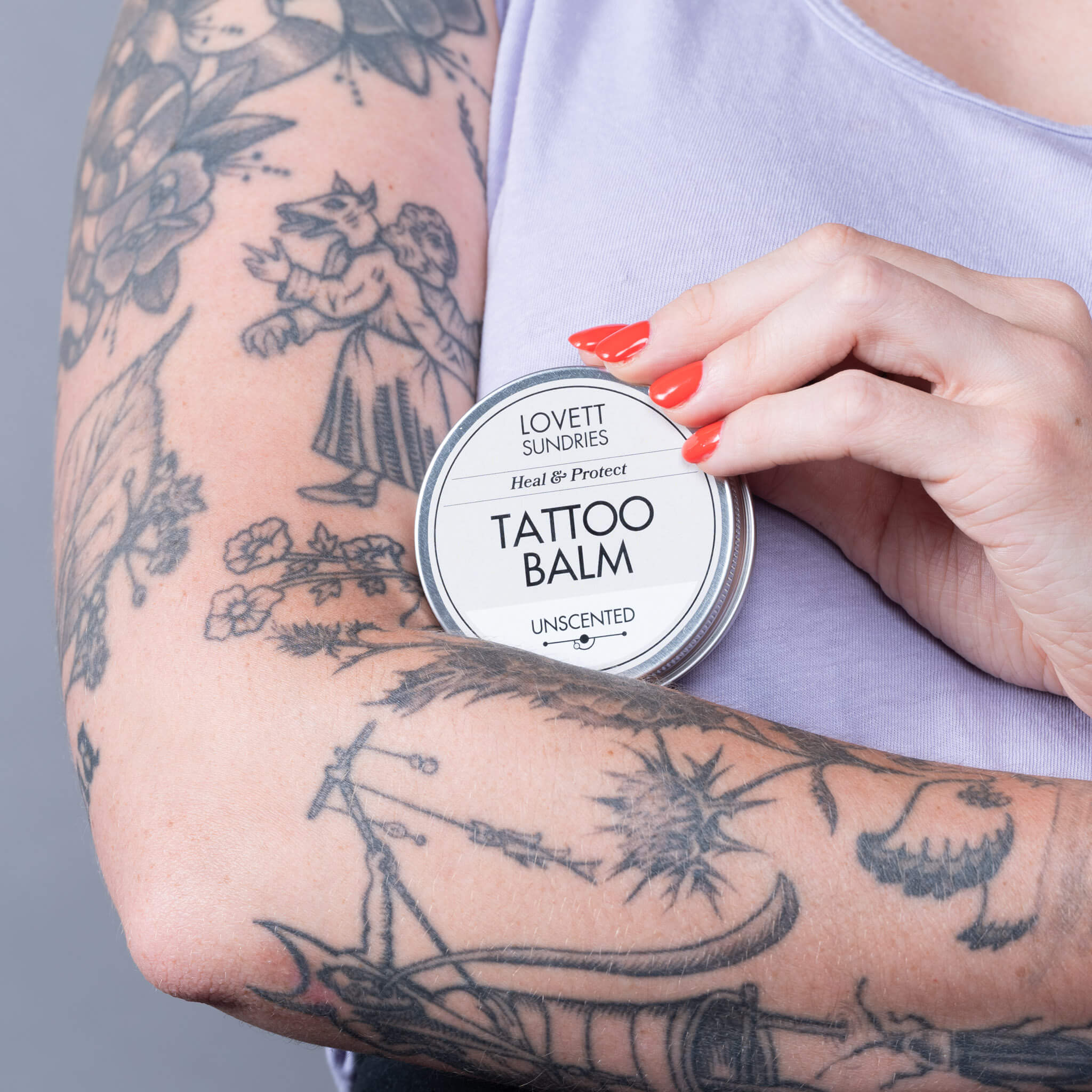 Kelly holding a tin of all natural tattoo balm.