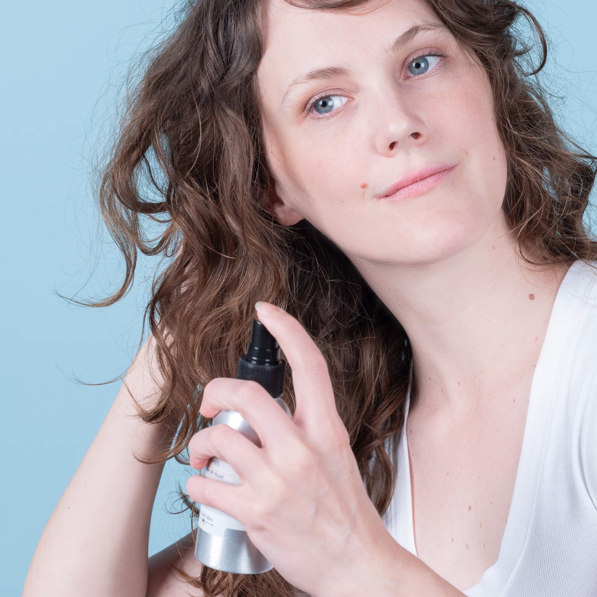 Steph spritzing all natural texturizing salt spray in her curly hair from a zerowaste bottle. 