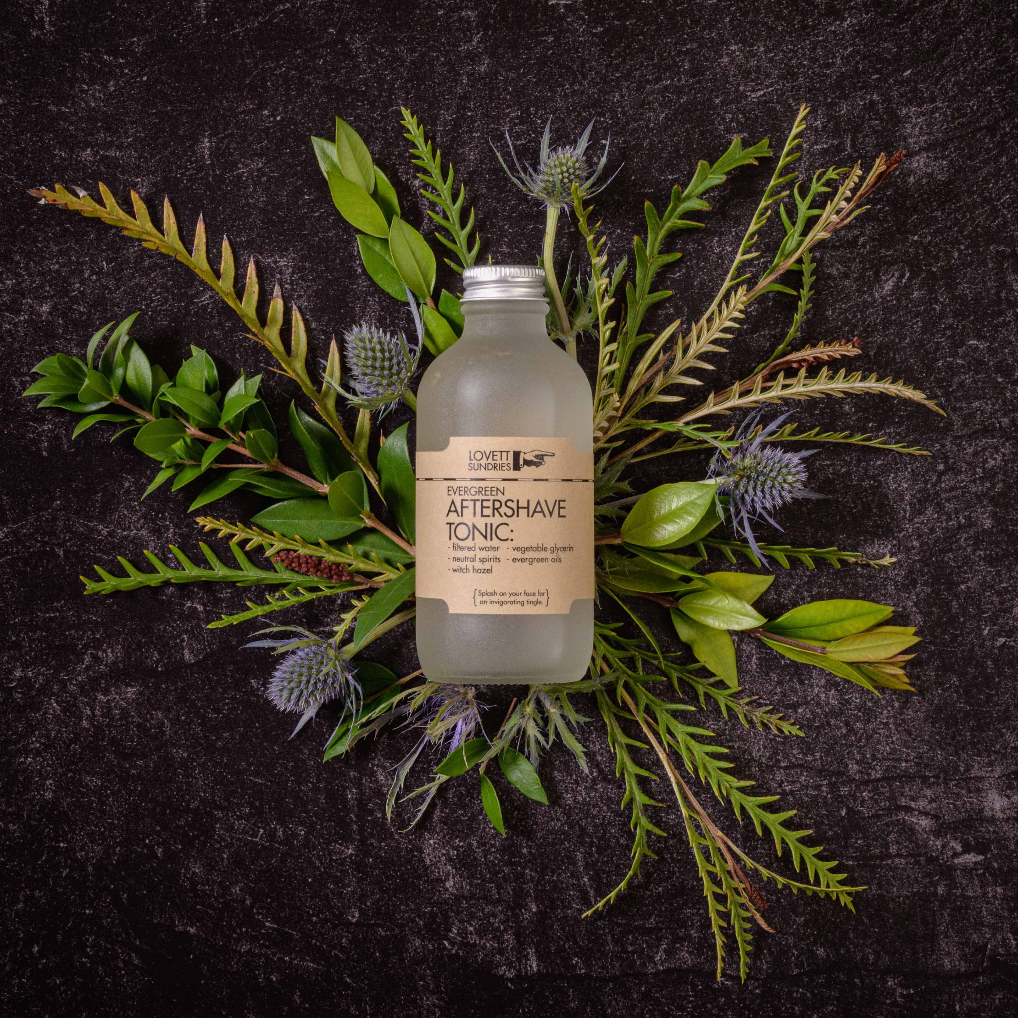A bottle of evergreen scented aftershave tonic on top of plants.