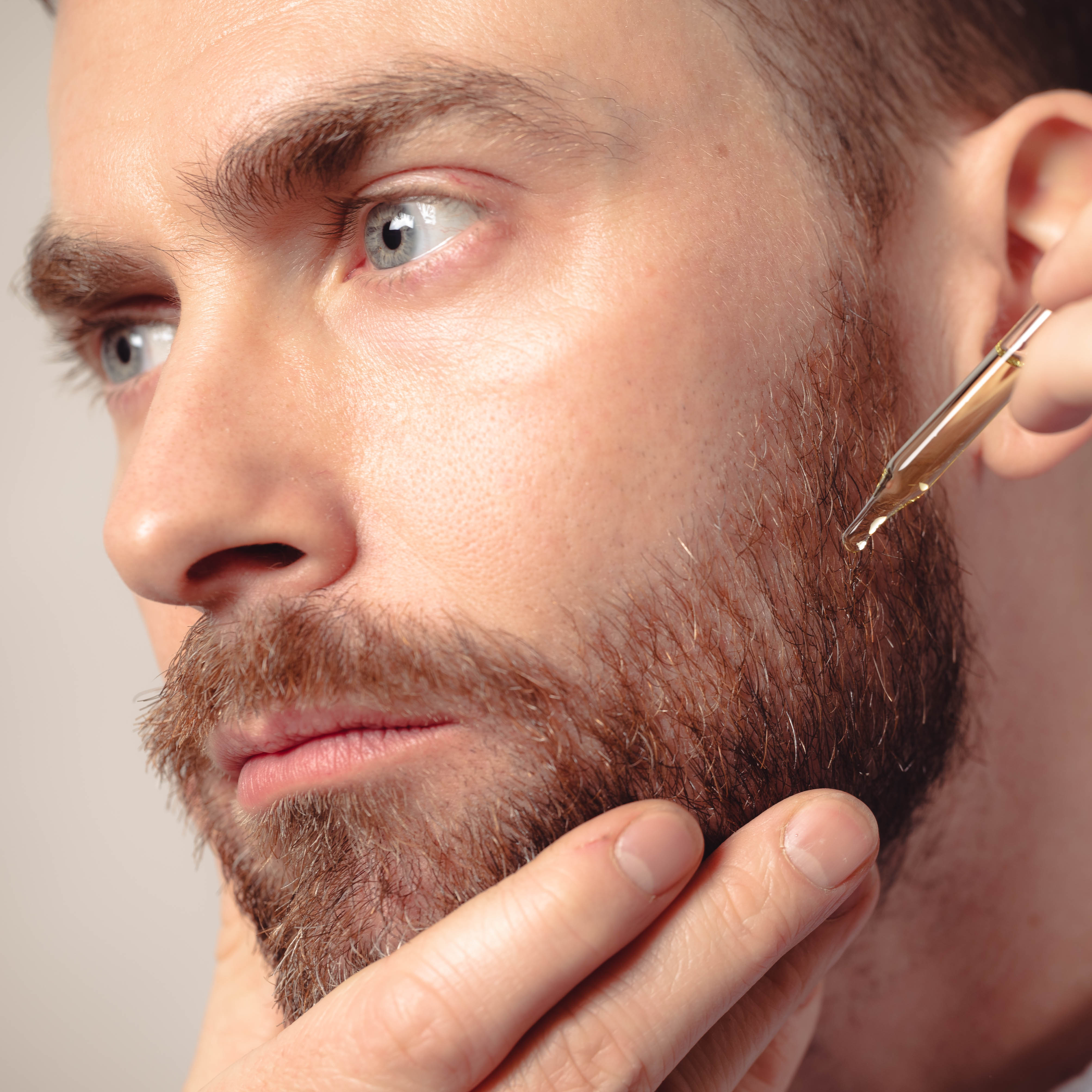 John applies a vial of Beard Oil directly to the whiskers on his cheek.
