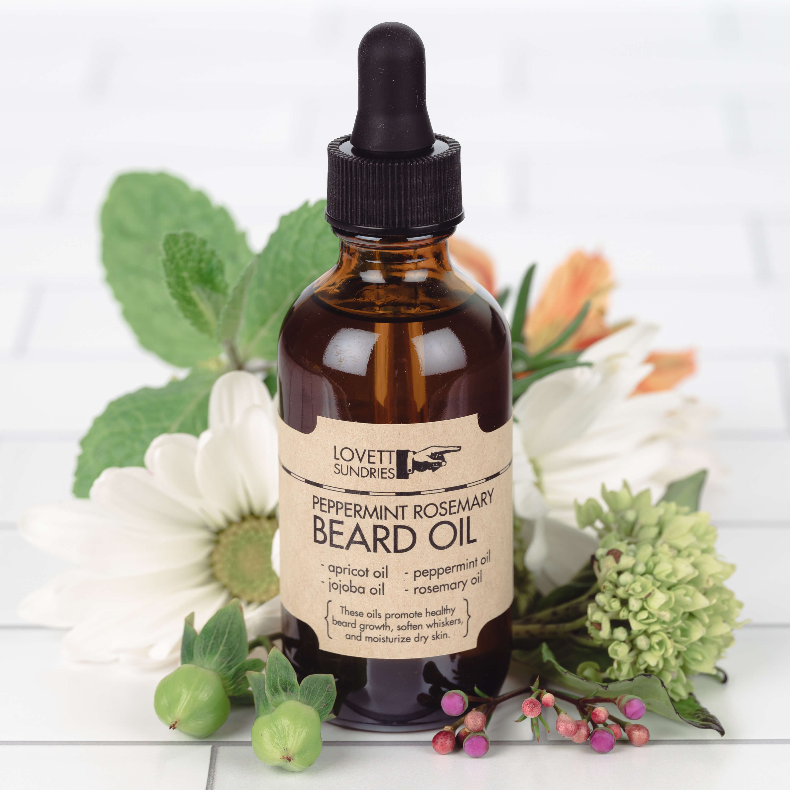 A bottle of peppermint rosemary scented beard oil on top of flowers and plants.
