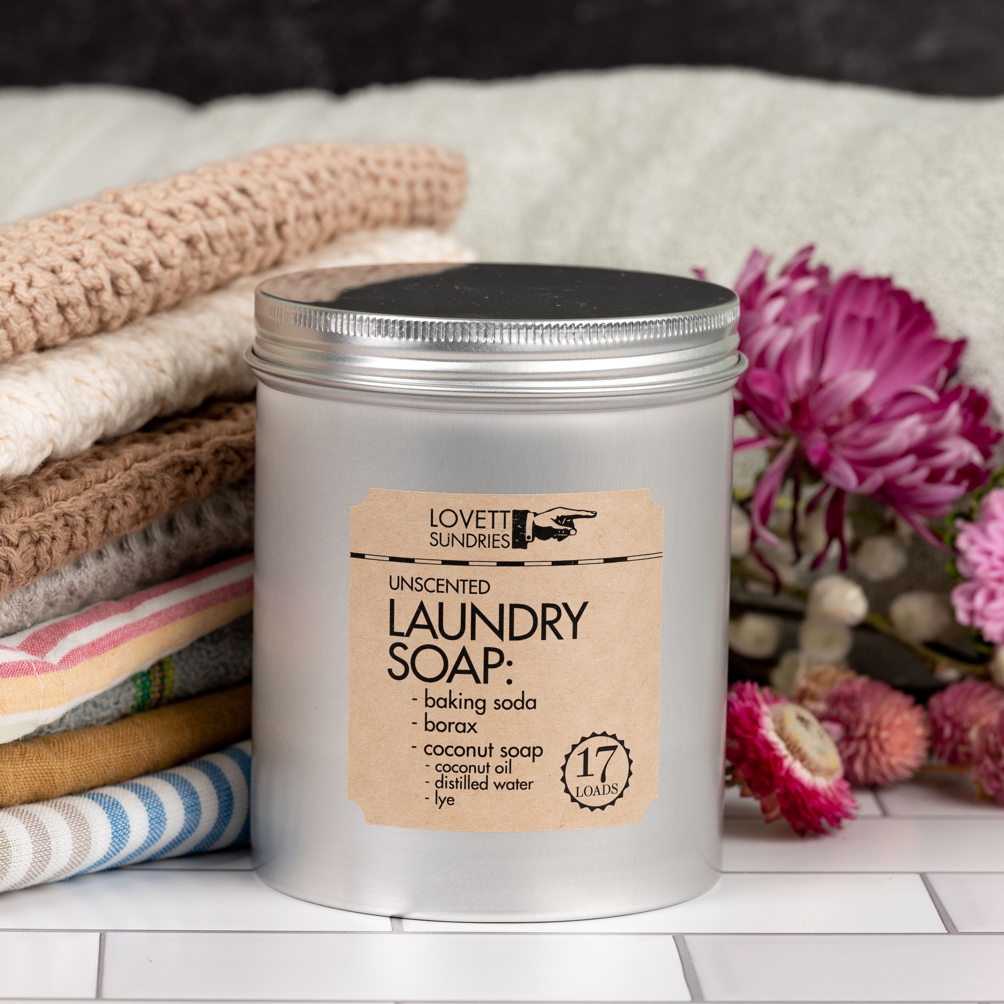 natural laundry soap in a tin with laundry and flowers in the background.